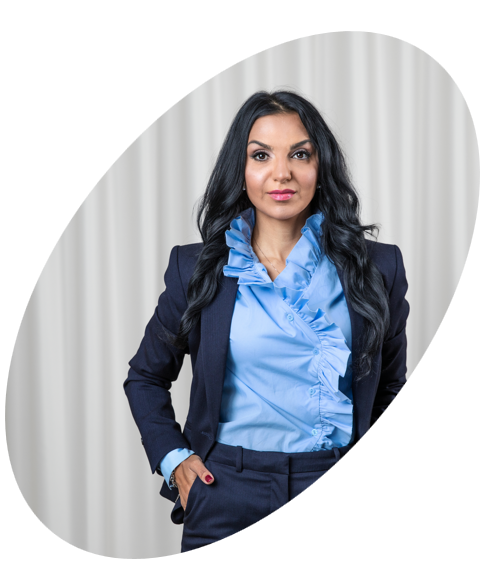 Kvinna i blå blus och mörk kostym framför en vit bakgrund