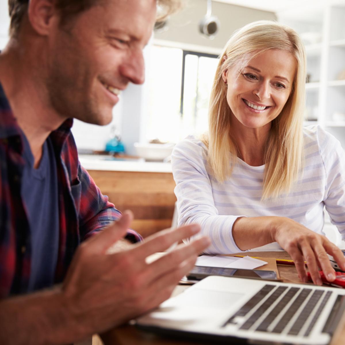 Två leende personer arbetar tillsammans vid en bärbar dator i ett ljust kontorsutrymme