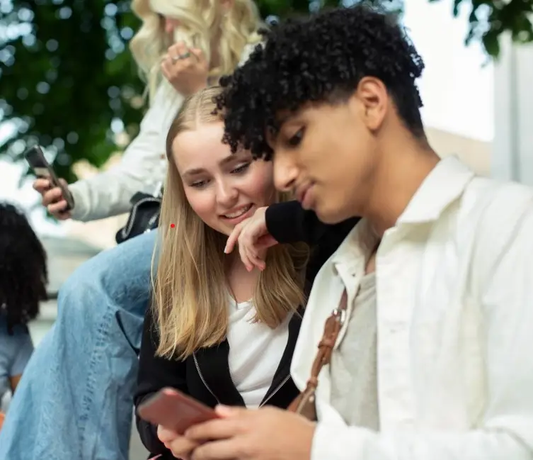 Ungdomar som använder smartphones tillsammans utomhus, vänskap och digitalt samspel