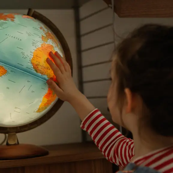 flicka står framför jordglob