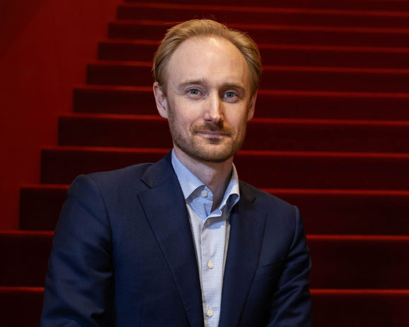 Man i mörk kostym framför röda trappor