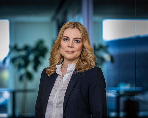 Kvinna i affärskläder står inomhus med suddig kontorsbakgrund