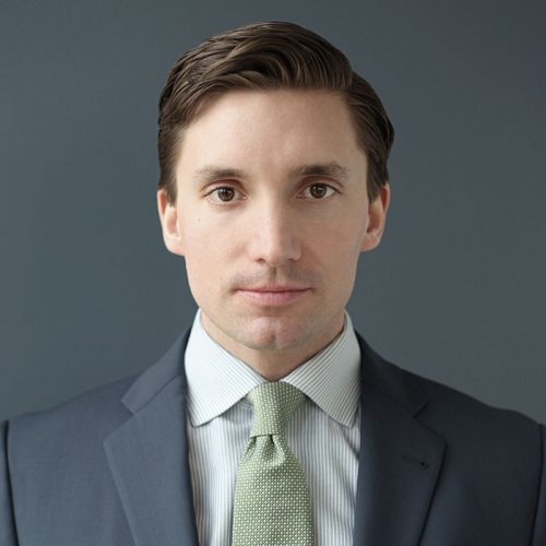 En man i kostym och slips mot en grå bakgrund