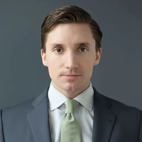 En man i kostym och slips mot en grå bakgrund