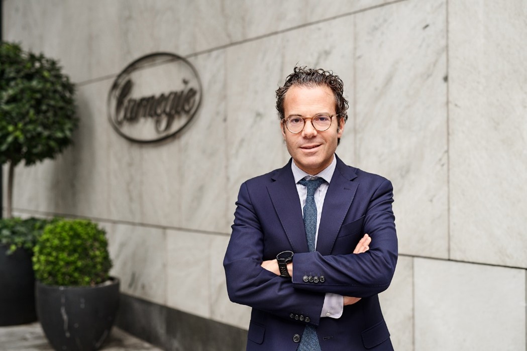 Man i kostym står framför Carnegie-skylt på marmorerad vägg