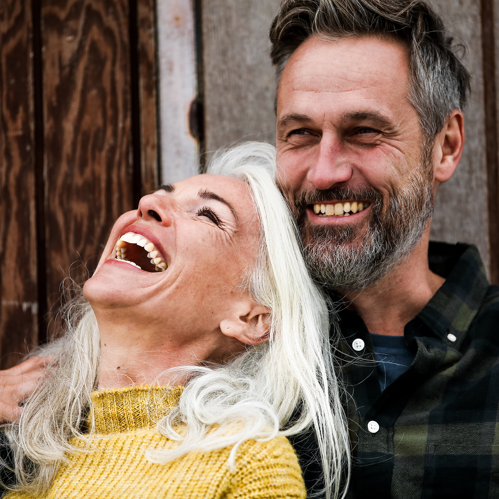 Ett glatt par i medelåldern skrattar tillsammans utomhus