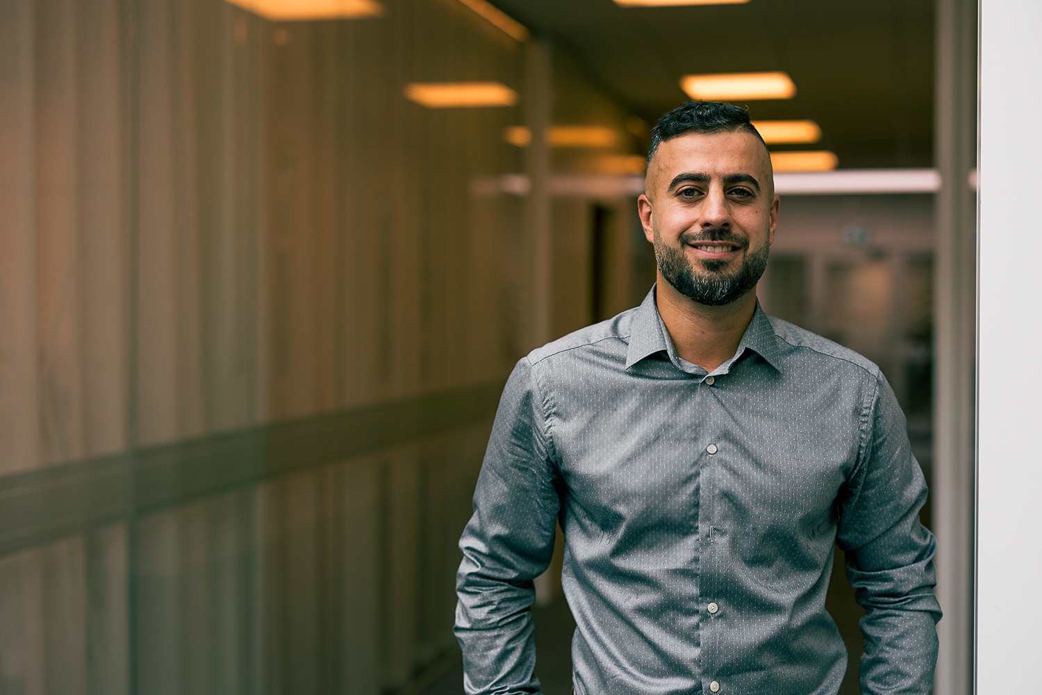 Man i grå skjorta ler i kontorsmiljö