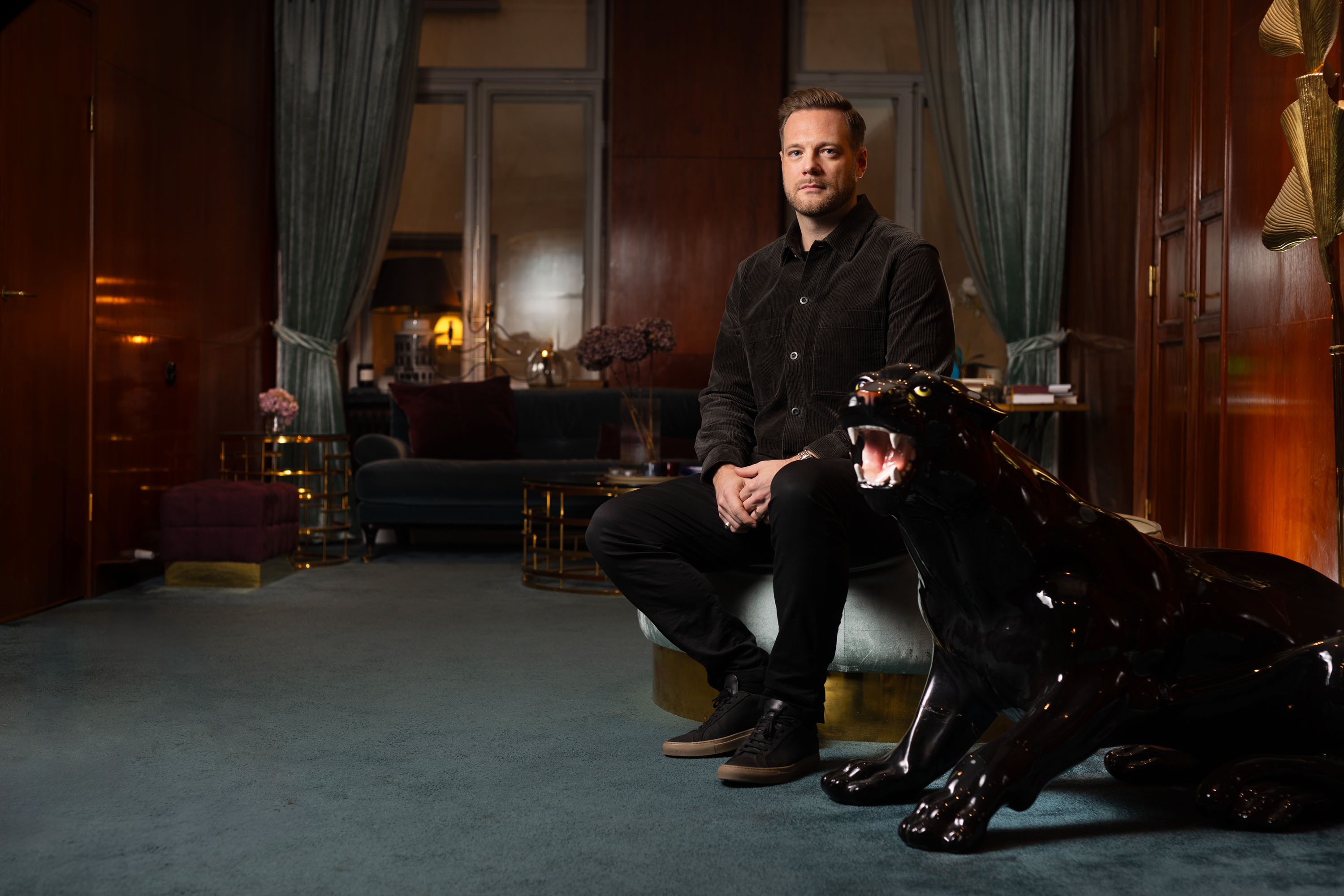 Man sitter i stilfullt inredd salong med glänsande svart panterstaty