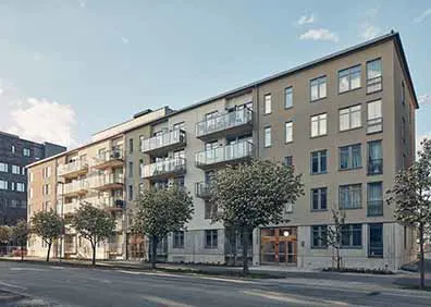 Flervåningshus med modern design och balkonger, omgiven av träd längs en stadsgata i Sverige