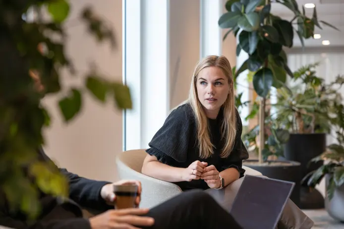 Kvinna i samtal med kollega i modernt kontor med grönska