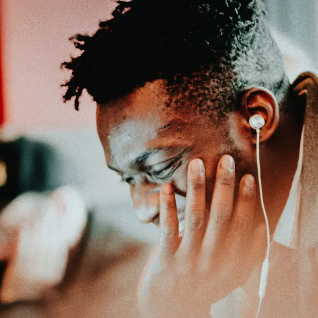 Man med hörlurar tänker djupt, närbild på ansikte mot suddig bakgrund