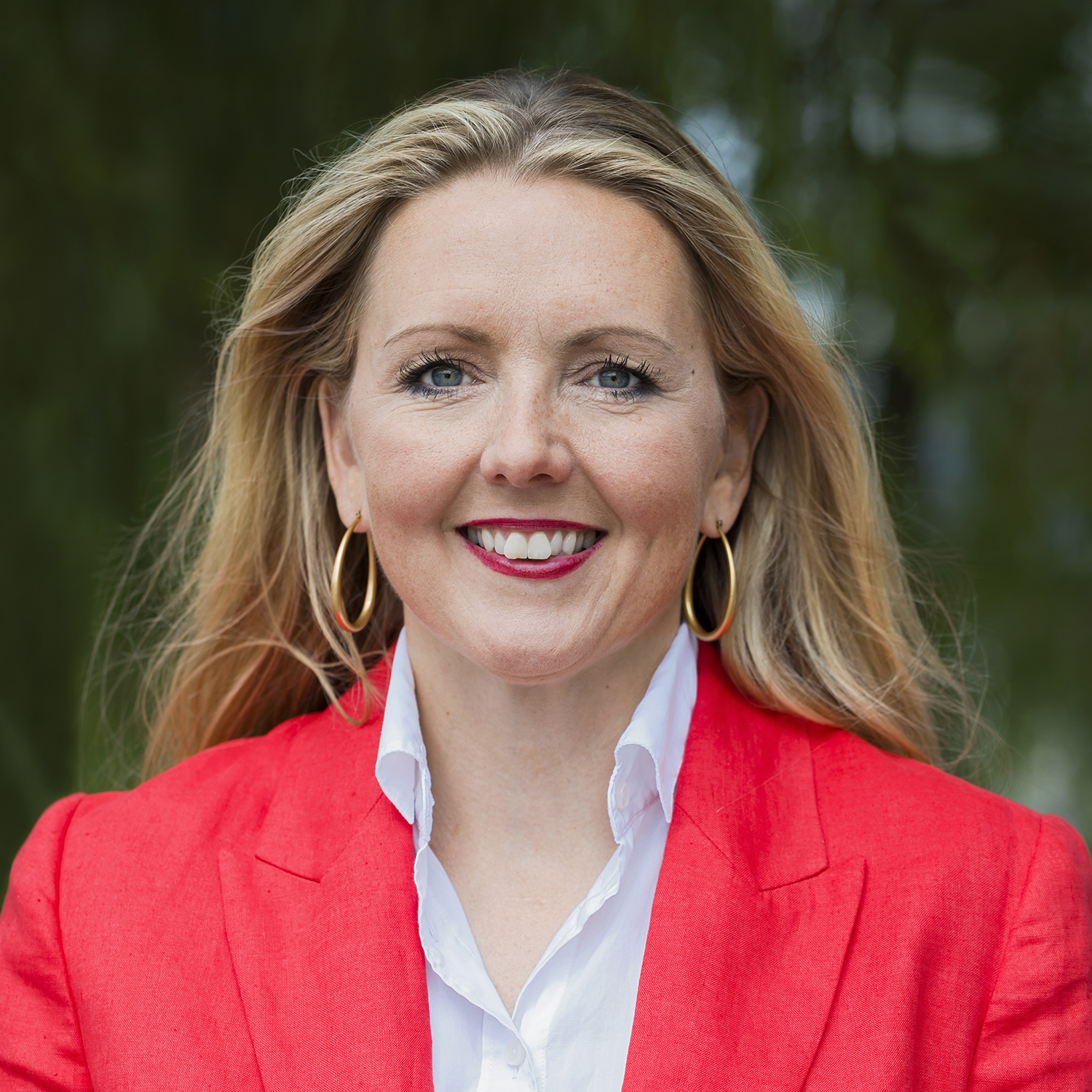 Kvinna i röd kavaj ler mot kameran